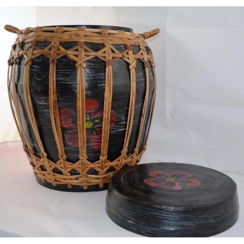 Black rattan and bamboo round lidded basket with woven wicker pattern, red flower designs on lid and sides, close-up.