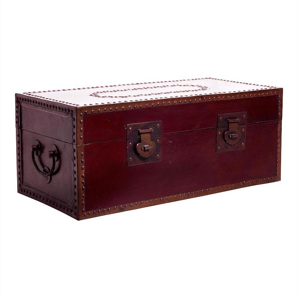 Close-up of red lacquer trunk with metal studs and dark reddish-brown handles, used as a coffee table.