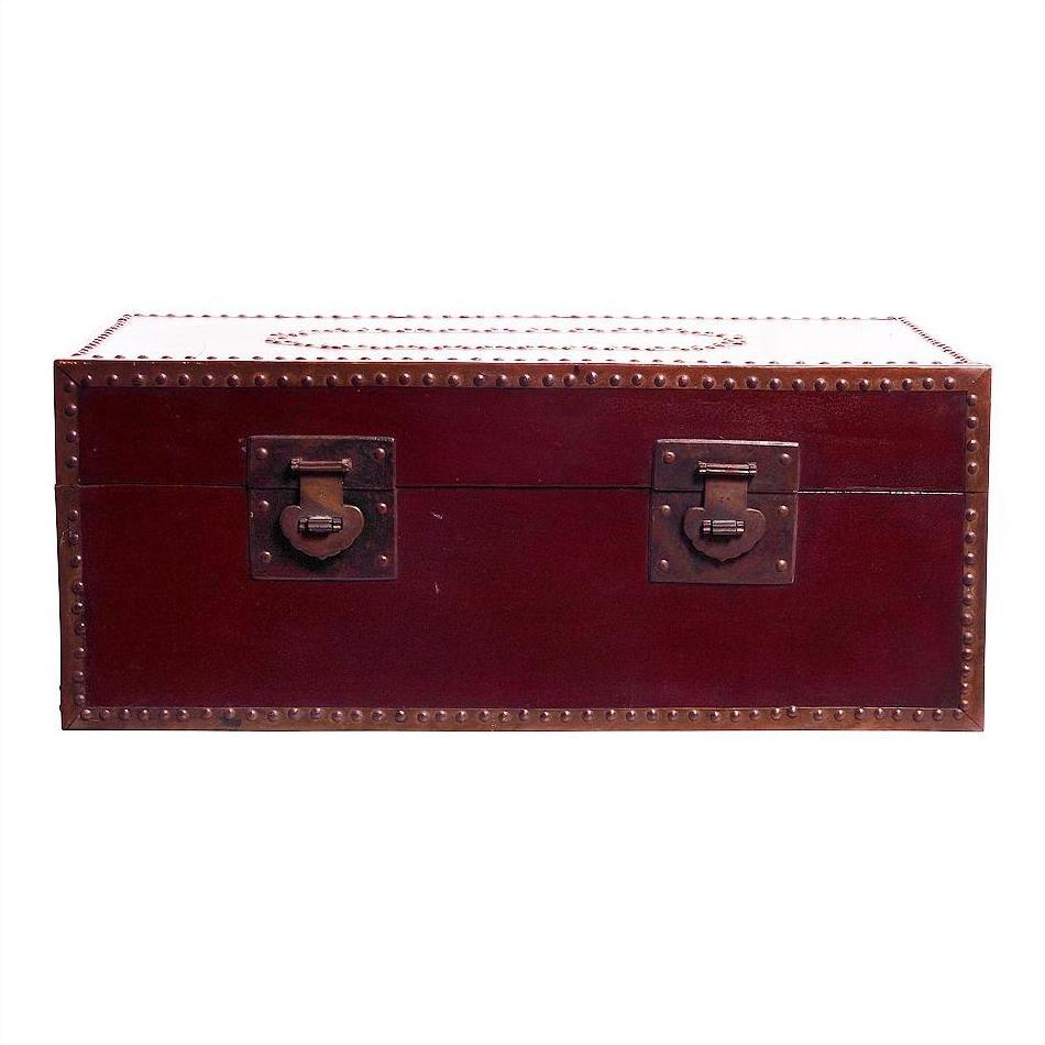 Red lacquer trunk with brown leather accents, metal studs, and two metal latches on front, close-up view.