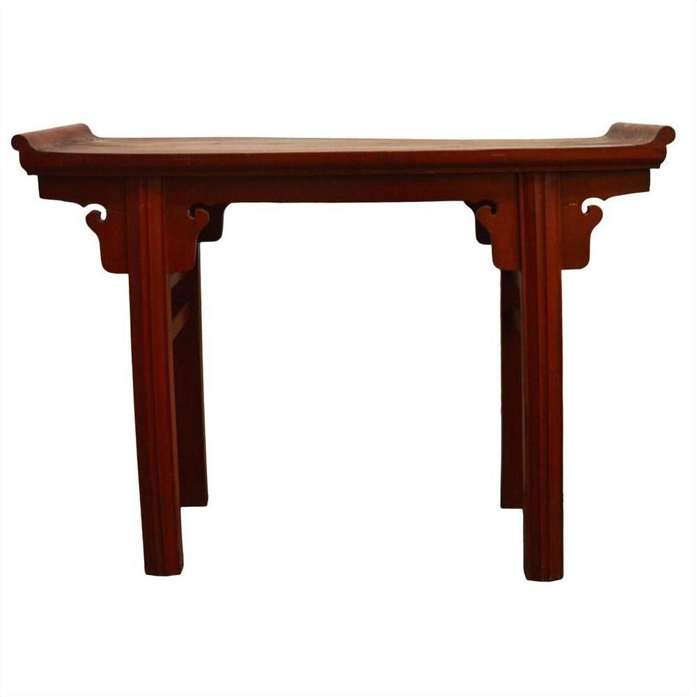 Close-up of red patina altar table with curved edges, scroll handles, and decorative legs in red finish.