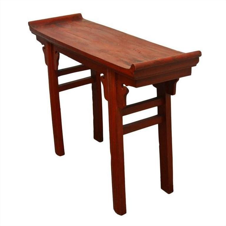 Red wooden altar table with red patina finish, scroll handles, curved ends, and four straight legs, close-up view.