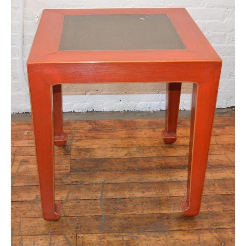 Red side tables with inset tile tops, wood flooring, white brick wall background.