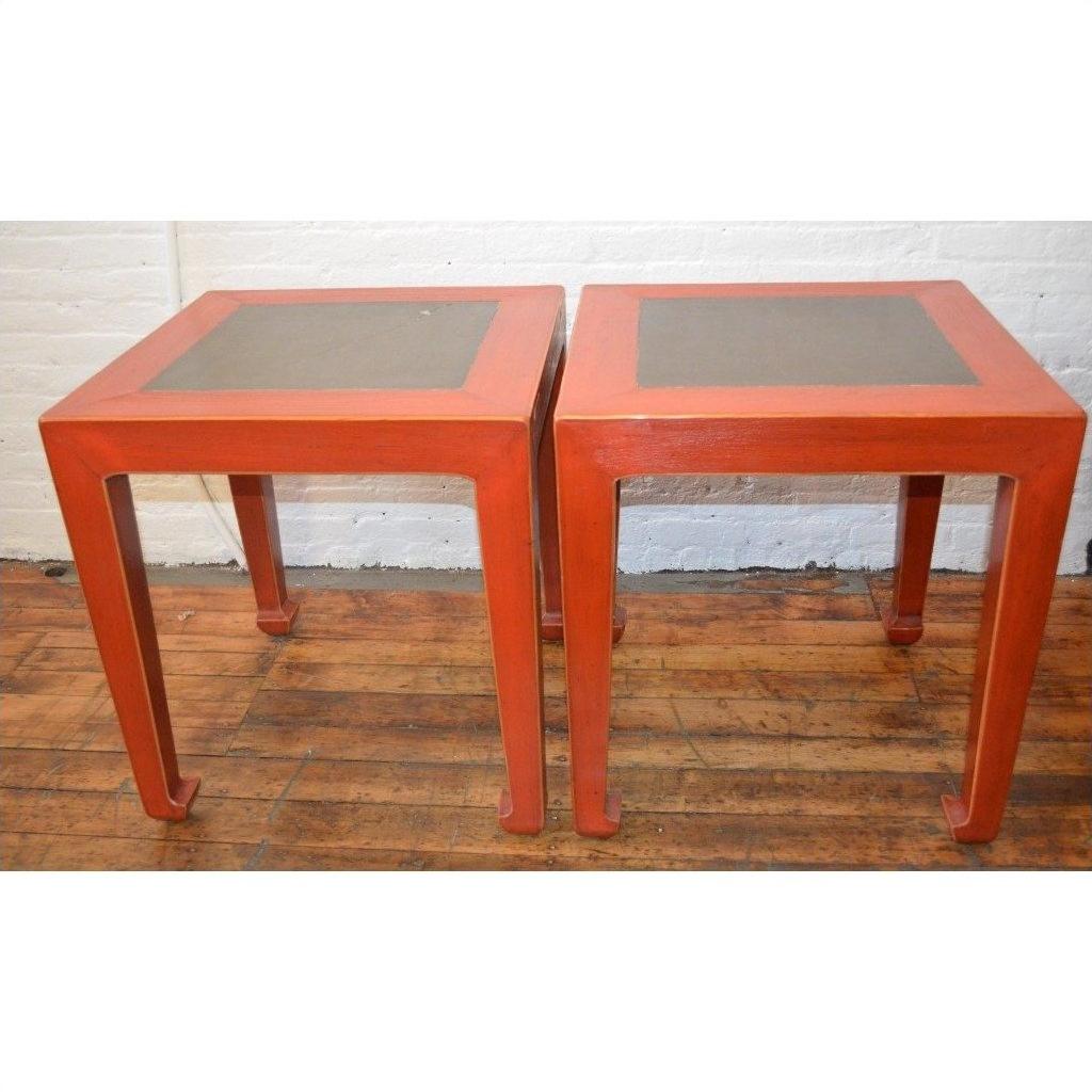 Red side tables with inset floor tiles on a wooden floor against a white wall, pair shown side by side.
