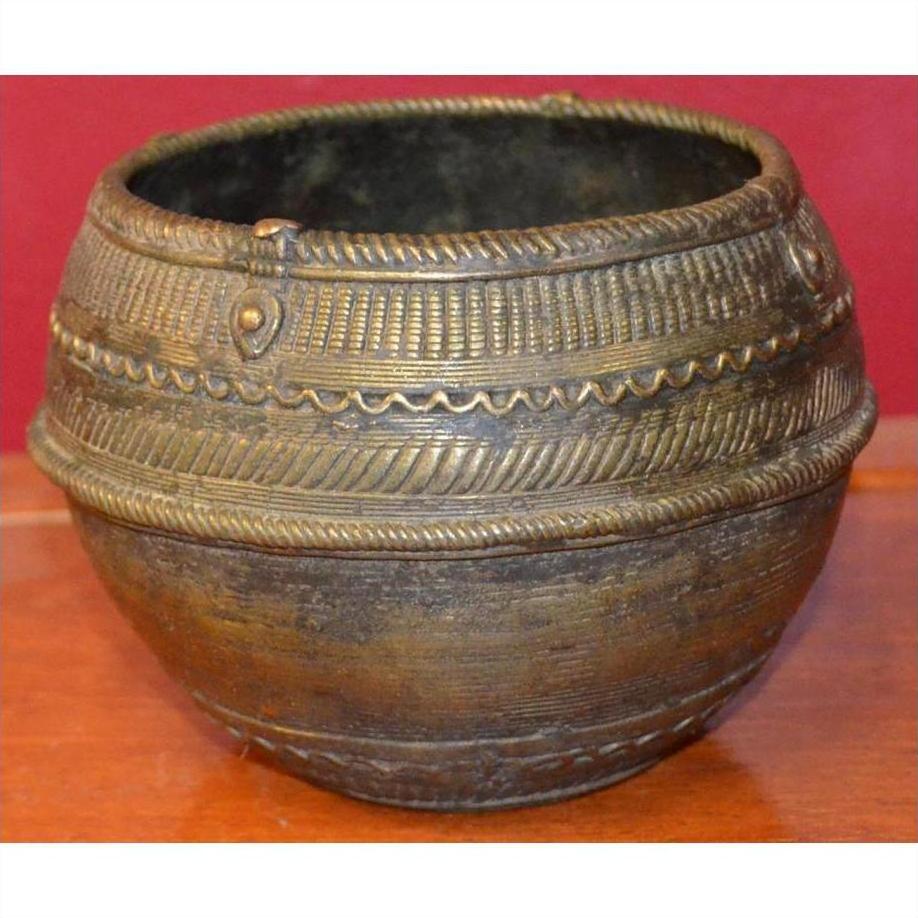 Brass rice measure bowl with engraved patterns on a wooden surface, close-up.
