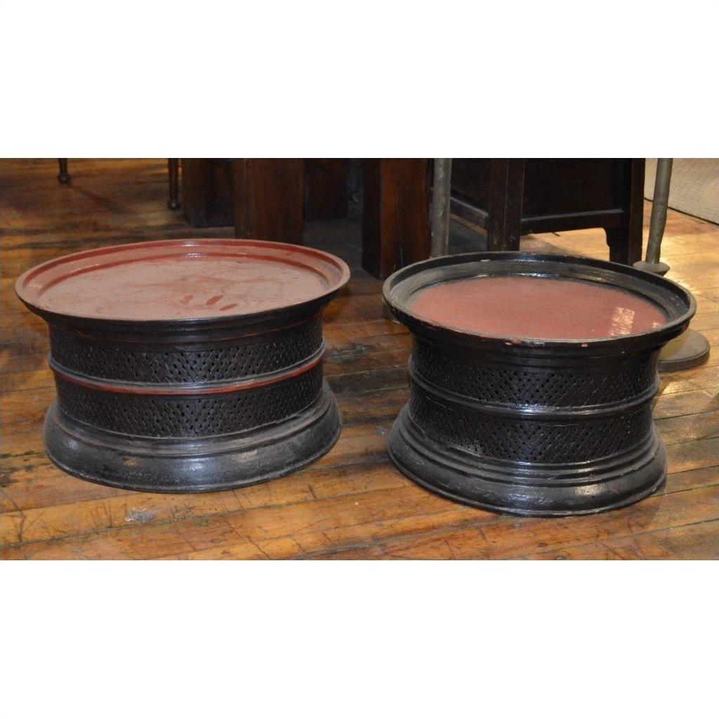 Black lacquered round offering trays with red tops on a wooden indoor floor, close-up view.