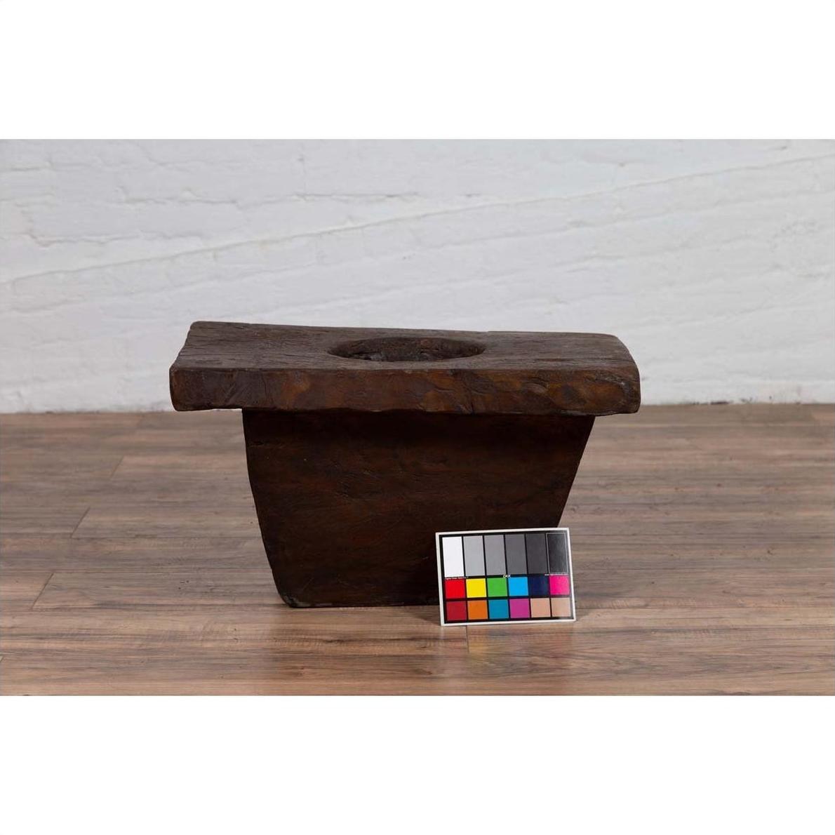 Brown wooden planter on wooden floor with color card in front, antique Indonesian style, early 20th century.