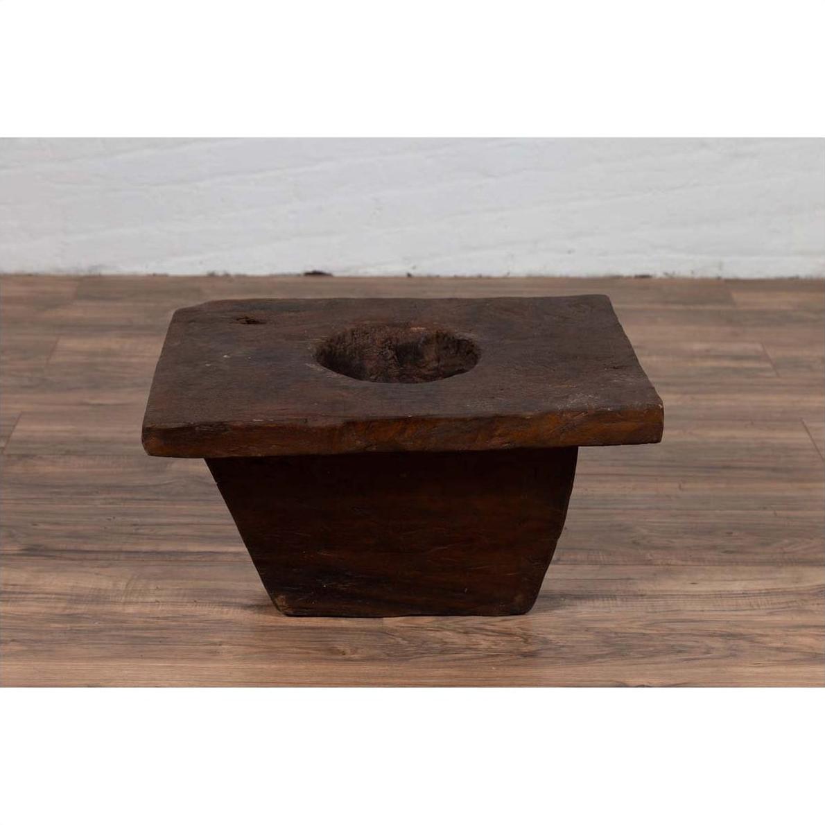 Brown wooden planter, antique Indonesian style, on a wooden floor indoors.