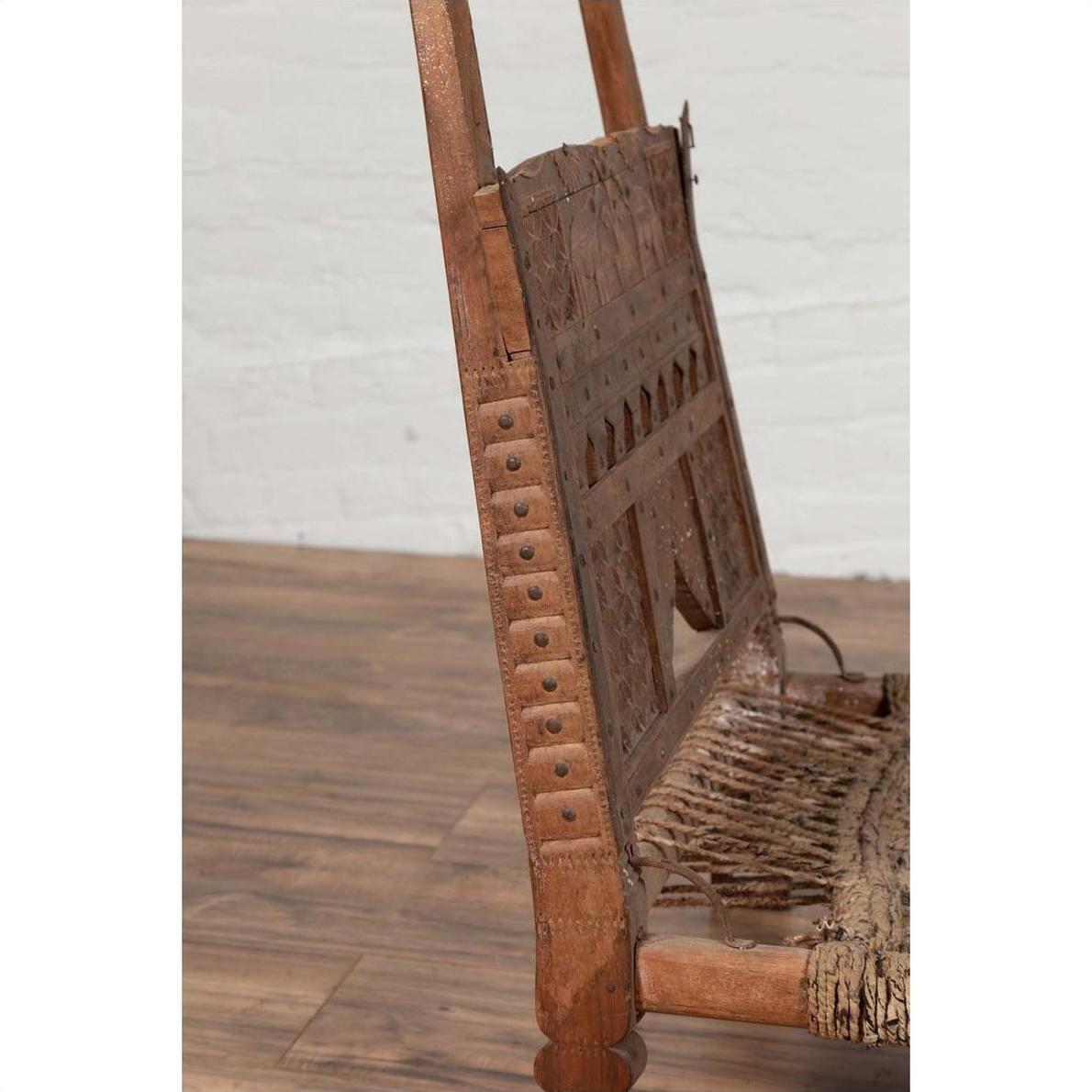 Close-up of brown wooden chair with rope seat and weathered finish on wooden floor indoors.