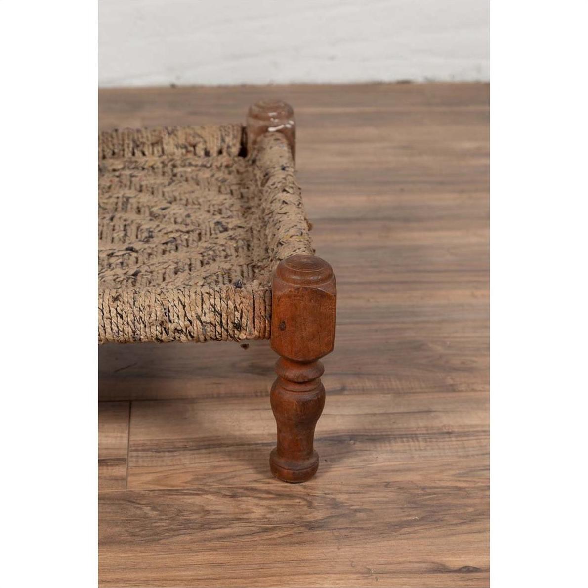 Close-up of brown wood and rope low chair leg on wooden floor.