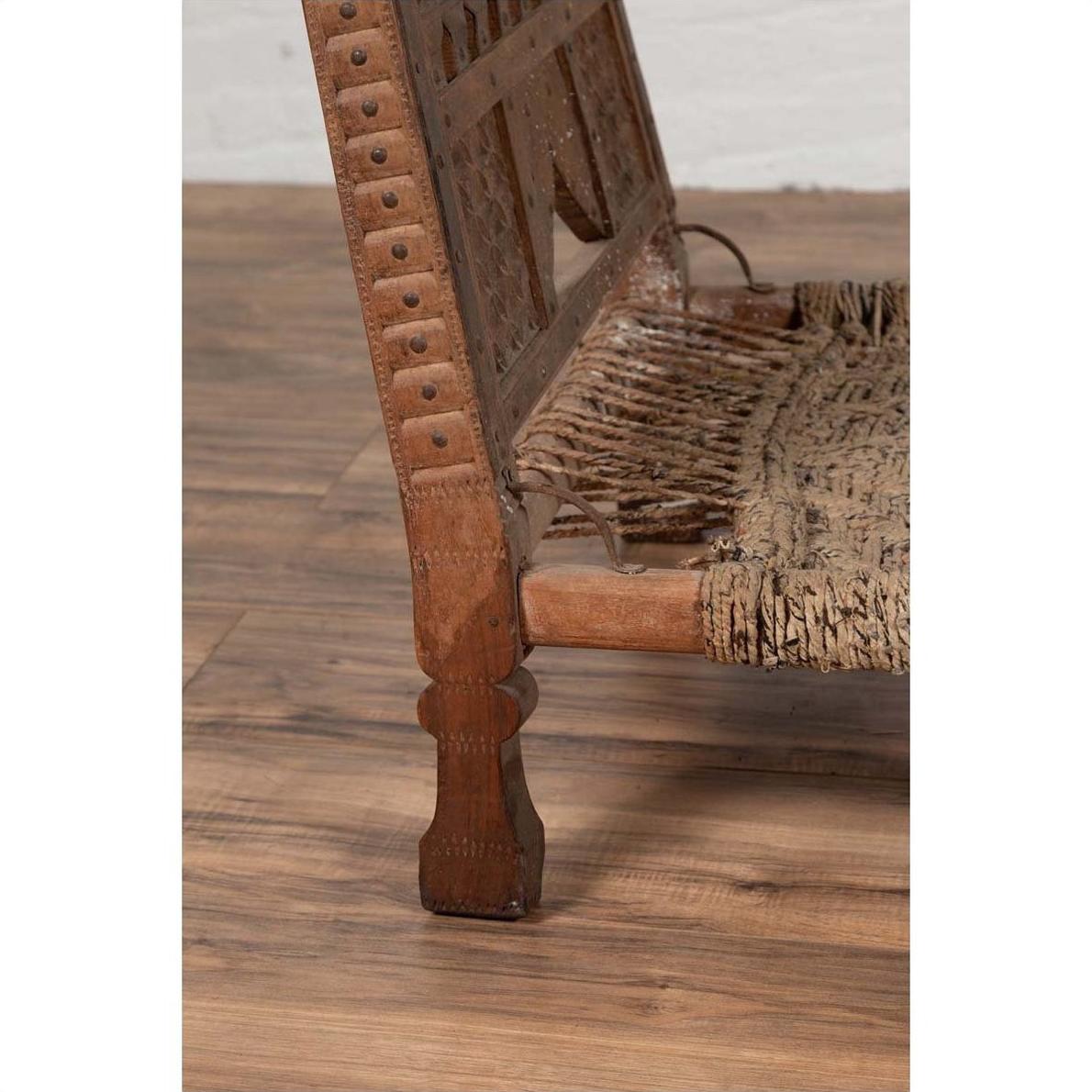 Close-up of brown wooden low chair with rope seat, rustic and weathered, on a wooden floor indoors.