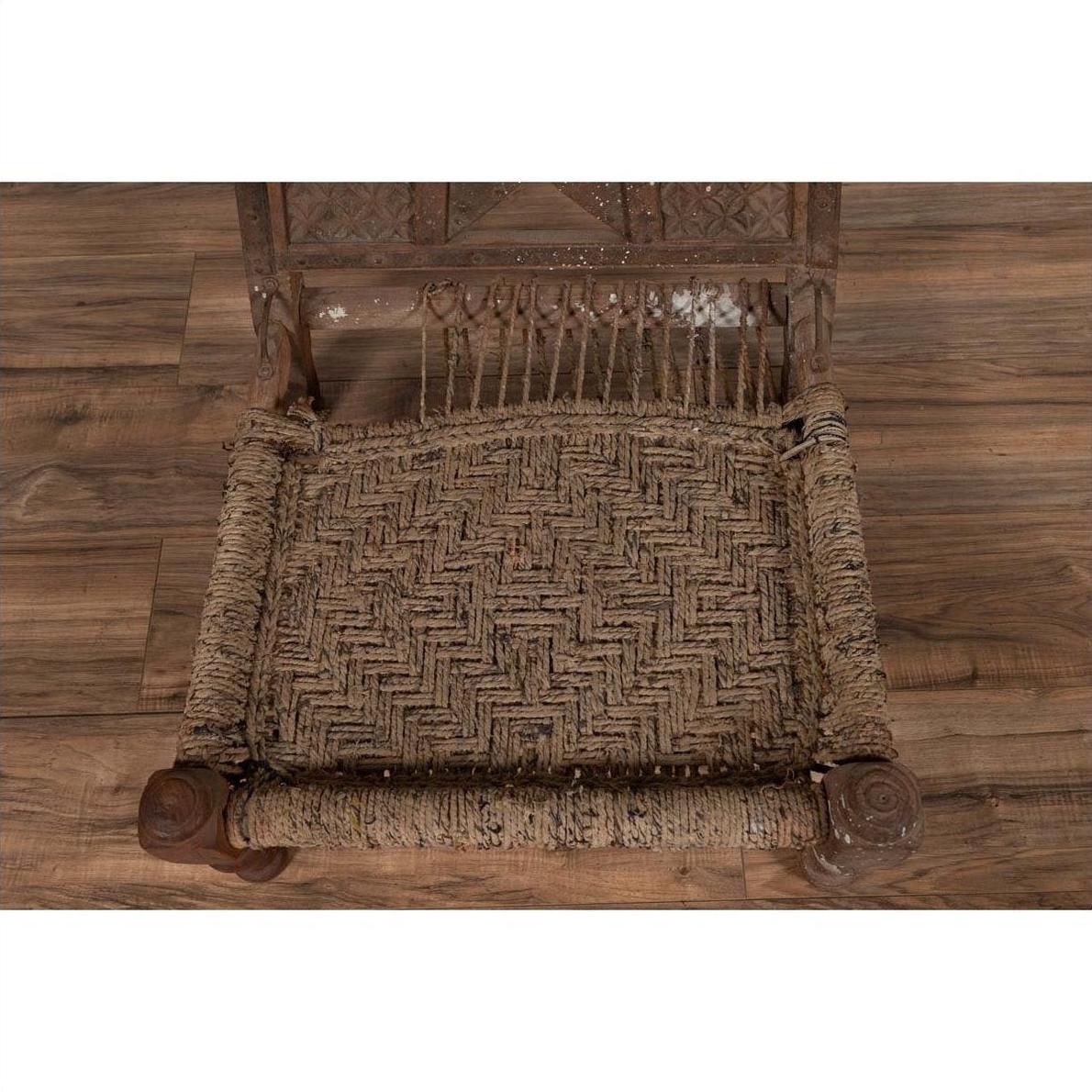 Brown wooden low chair with rope seat and weathered finish on a wooden floor.