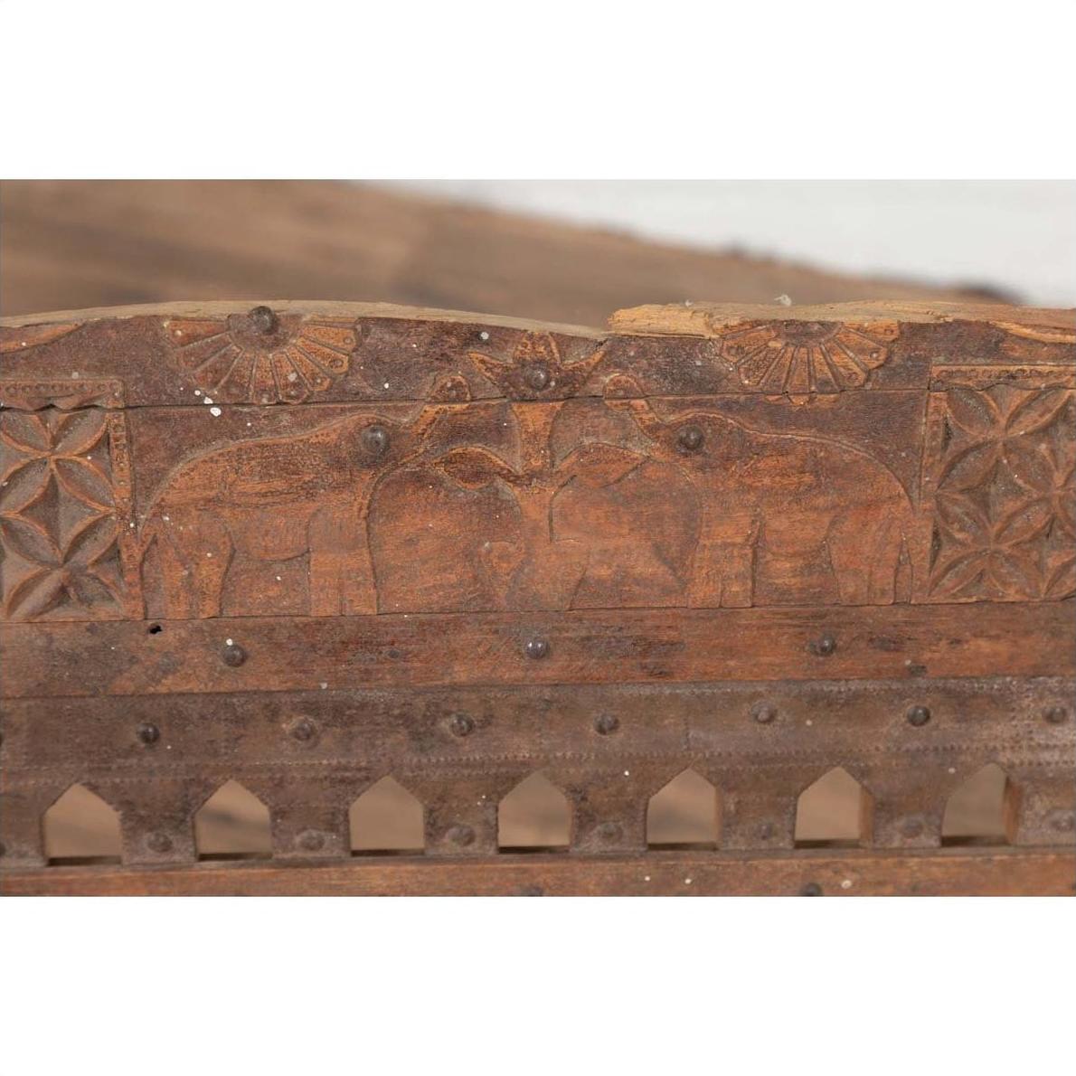 Brown wood and rope low chair with weathered finish and carved elephant panel accents, indoor setting.