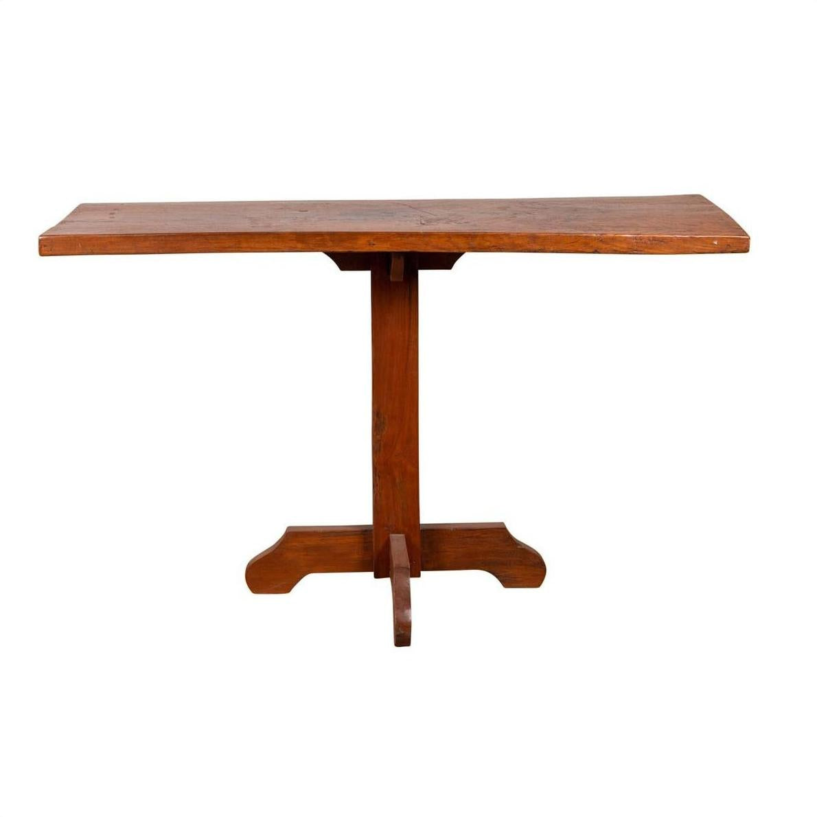 Brown wooden Indonesian console table with single plank top and pedestal base, on white background.