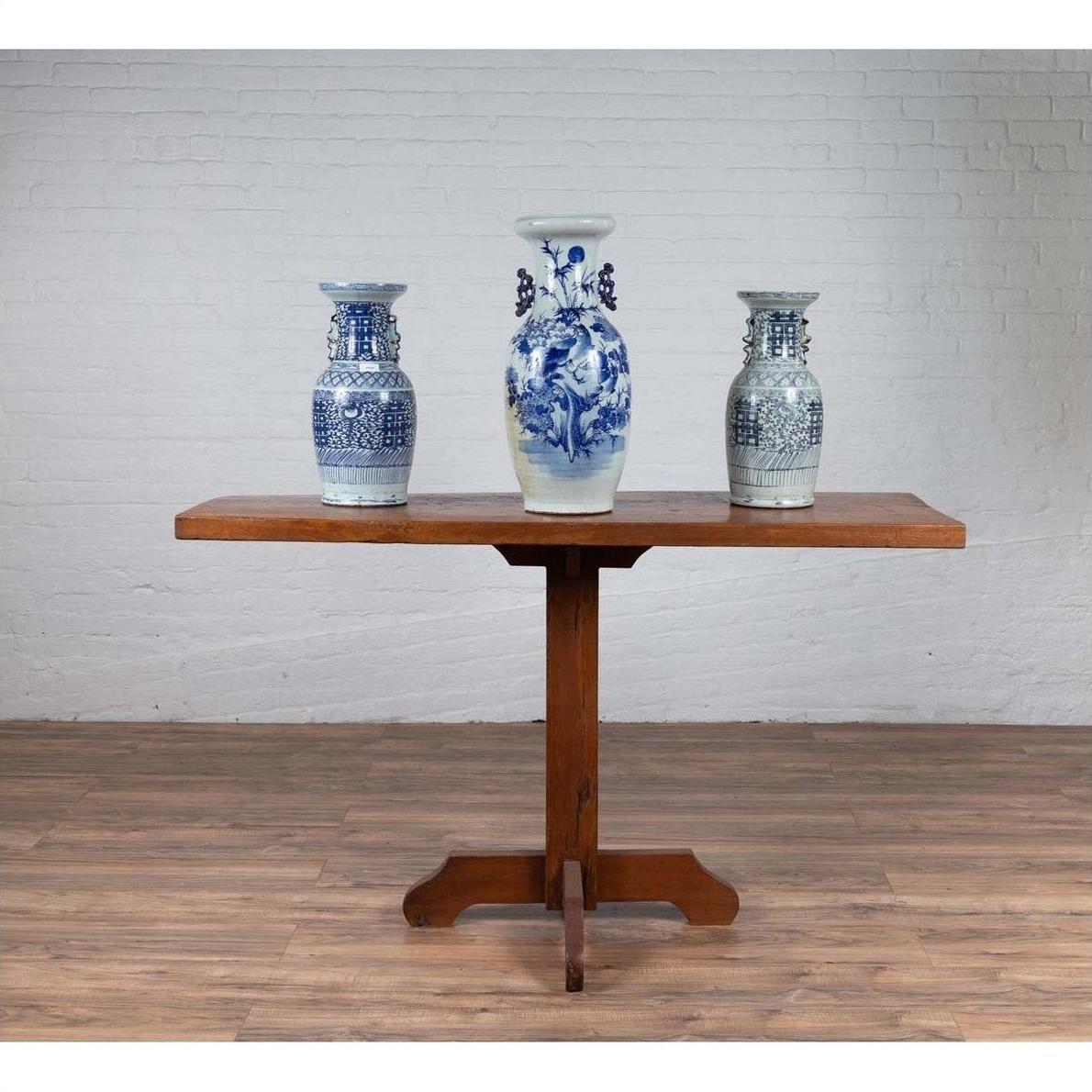Blue and white ceramic vases on rustic Indonesian wooden console table with single plank top and pedestal base.