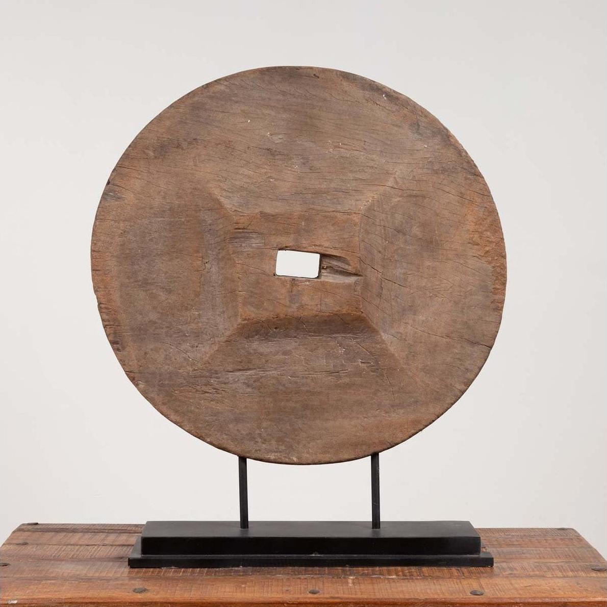 Brown wooden ox cart wheel from Thailand on a black painted base.