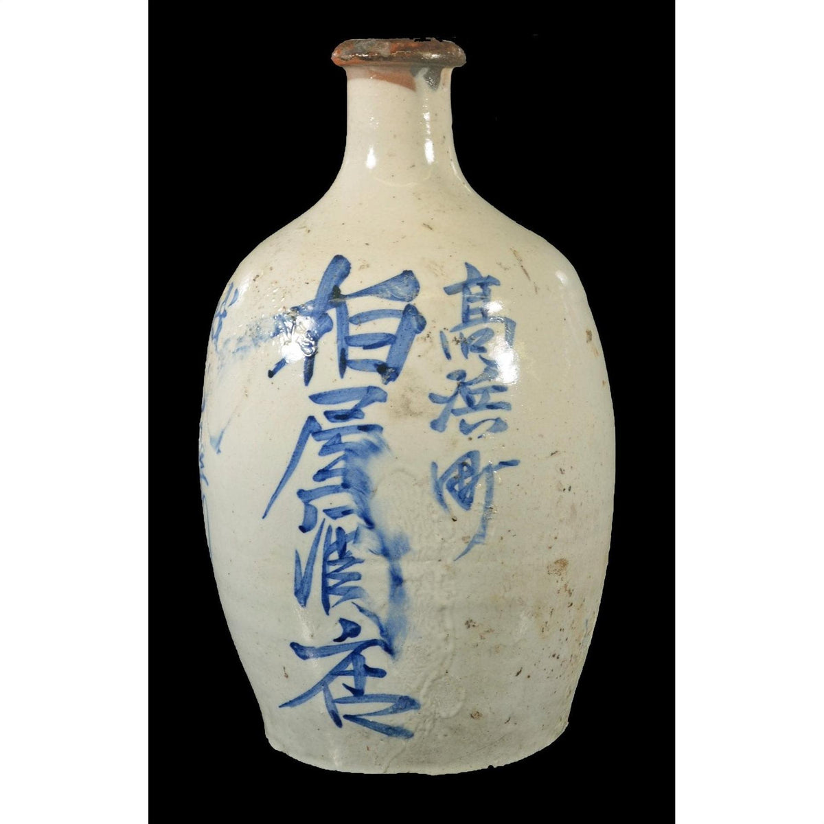 Close-up of a white ceramic sake jar with blue vertical kanji on a black background.