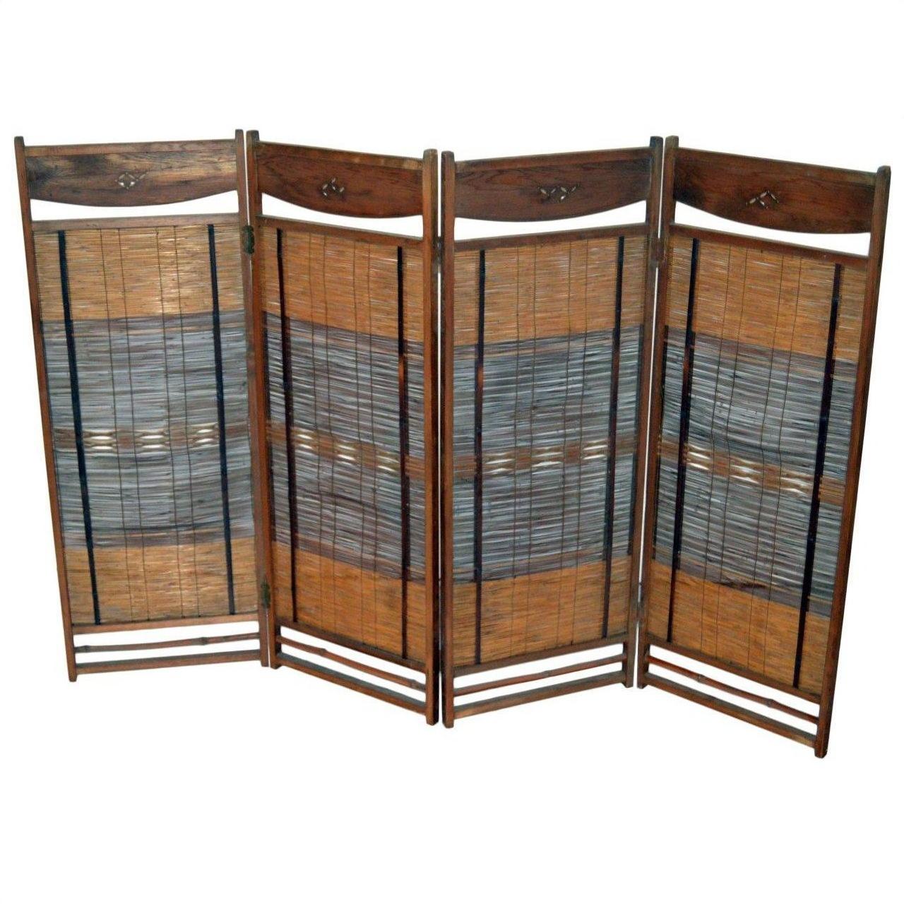 Brown wooden and bamboo folding room divider with woven panels, freestanding in a living space setting.