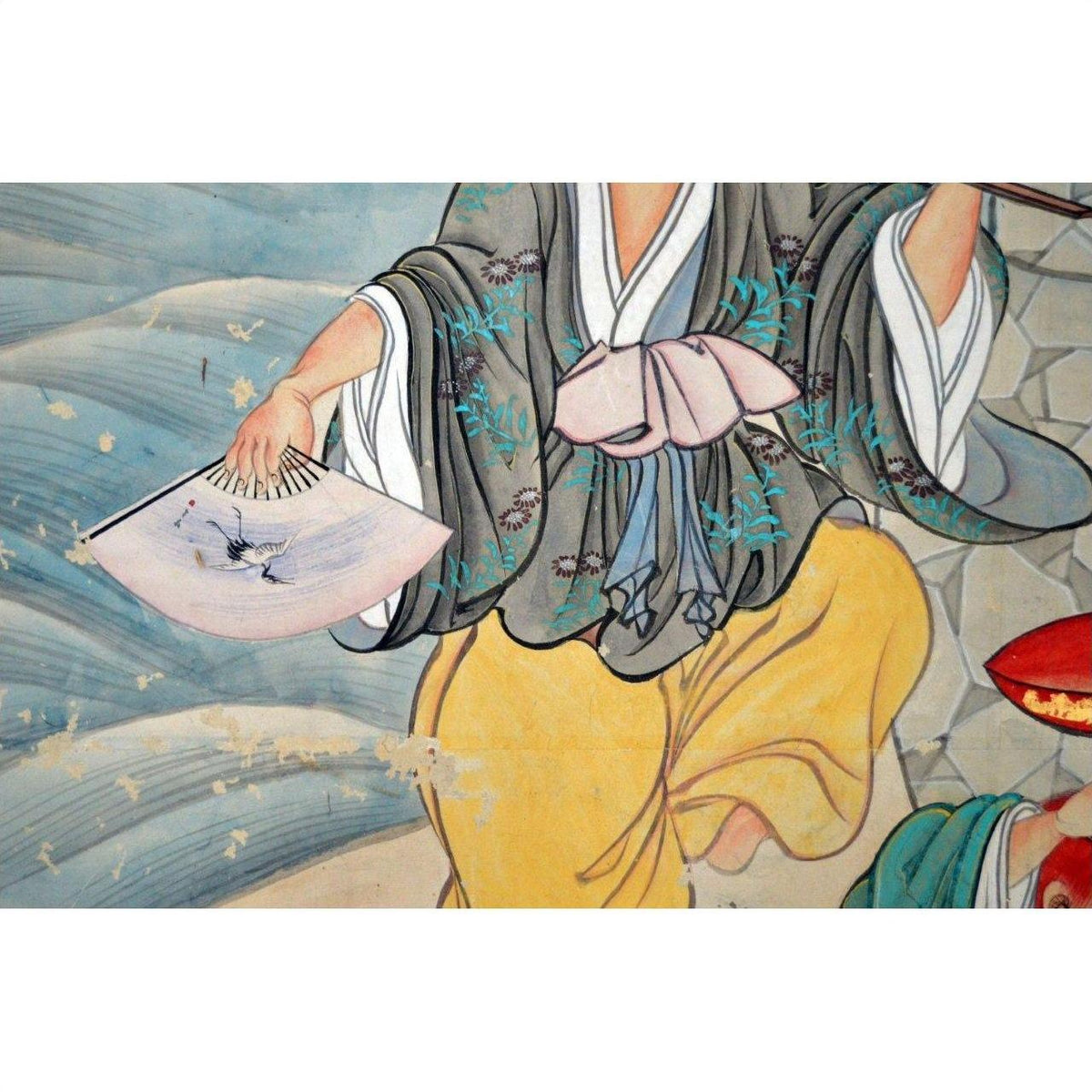 Person in colorful traditional clothing holding a feather bird fan in front of a vintage Japanese 2-panel screen indoors.