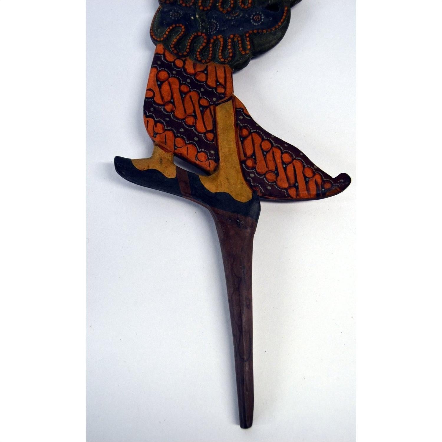 Close-up of painted wooden legs with intricate patterns on three Indonesian Wayang Kulit shadow puppets.