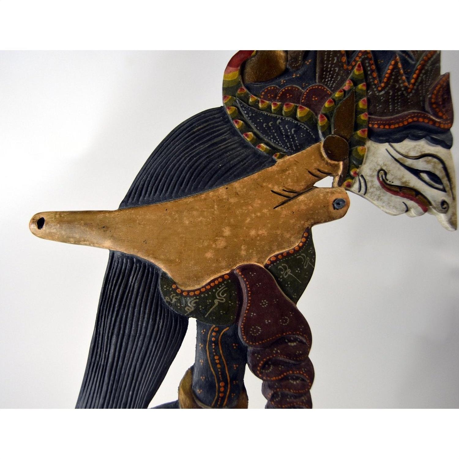 Close-up of three colorful wooden Wayang Kulit shadow puppets with detailed carvings.