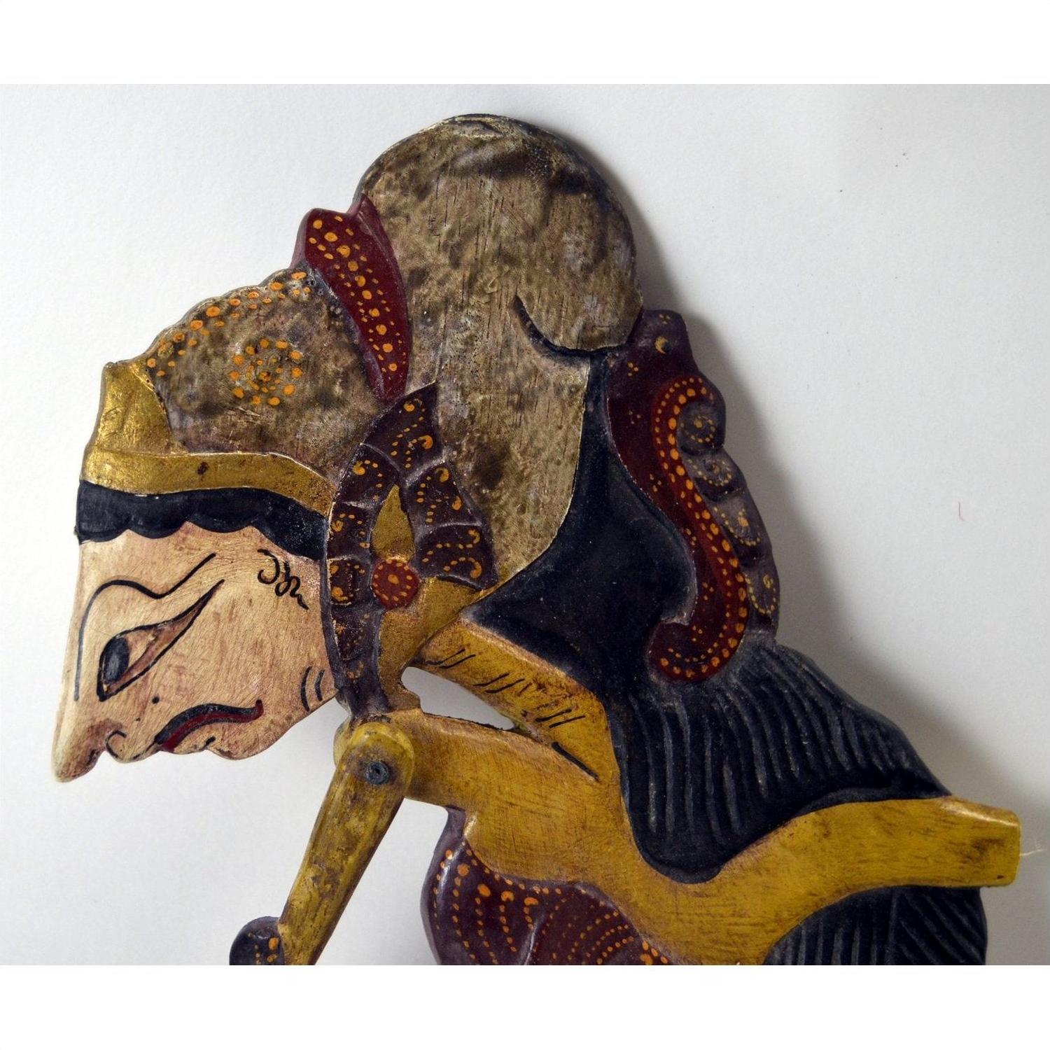 Brown wooden Indonesian Wayang Kulit shadow puppets with painted details, profile view on white background.