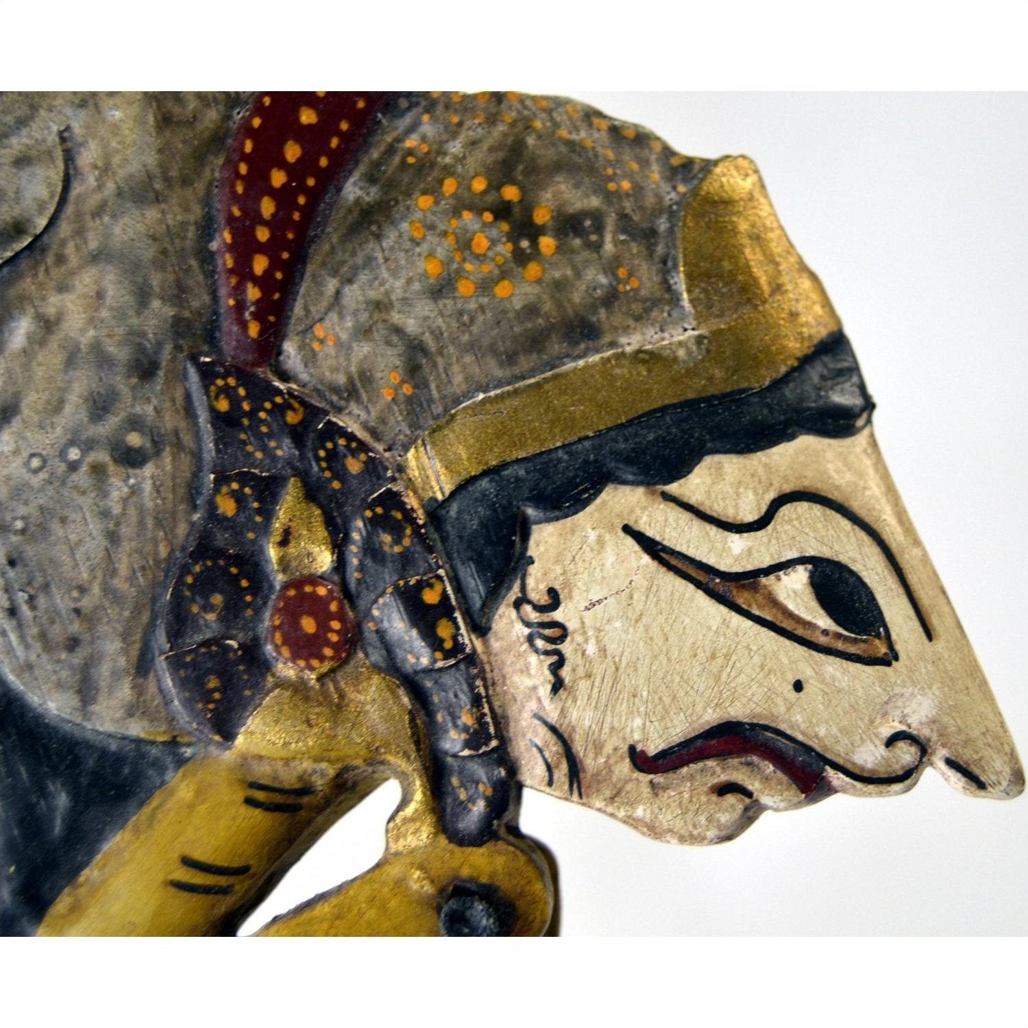 Close-up of three wooden Wayang Kulit Indonesian shadow puppets with intricate patterns and painted details.