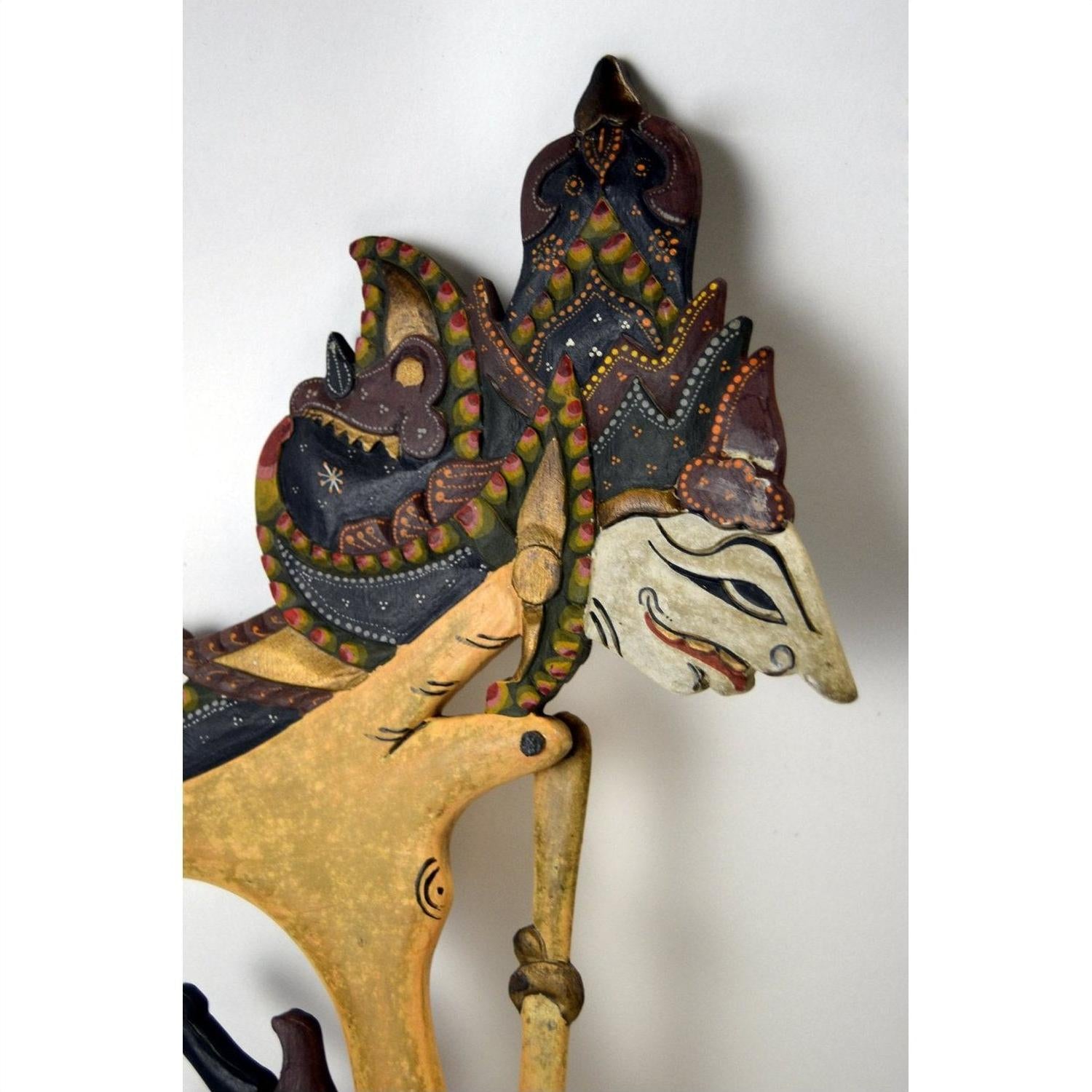 Brown wooden Wayang Kulit Indonesian shadow puppets with painted details, set of three on white background.