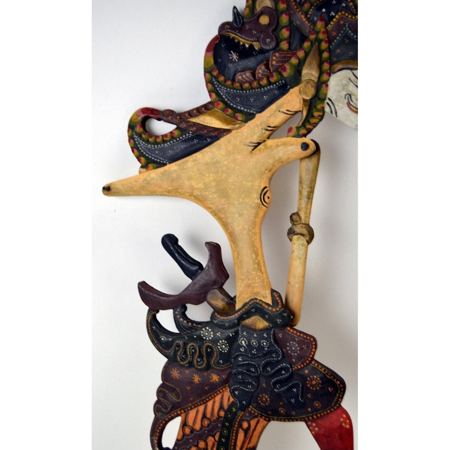 Set of three wooden Wayang Kulit Indonesian shadow puppets with intricate designs on a plain white background.