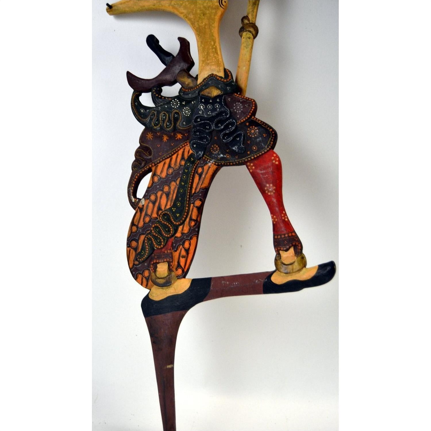 Black and orange wooden Wayang Kulit shadow puppets set of three, ornate costumes, close-up on white background.