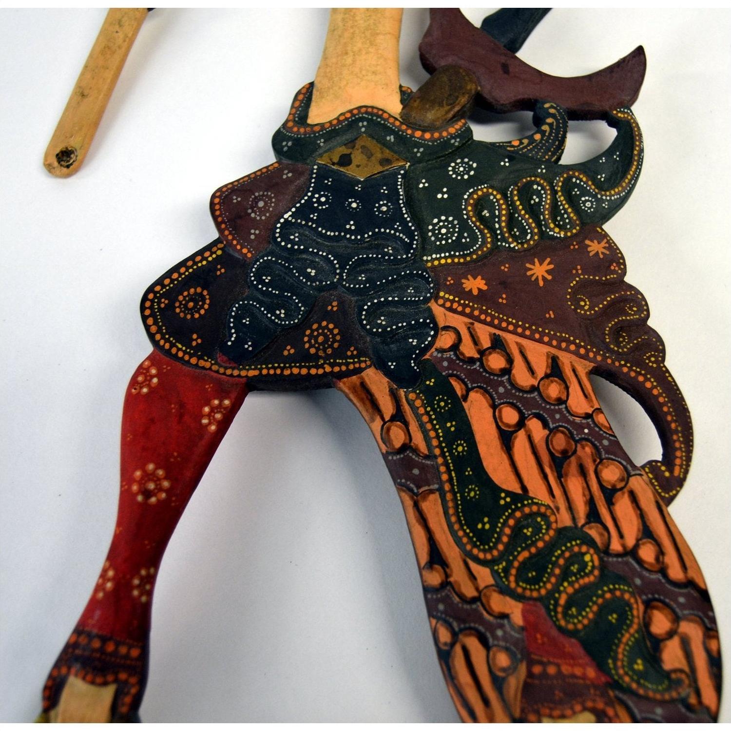 Close-up of red, orange, green, and black wooden Wayang Kulit shadow puppets.