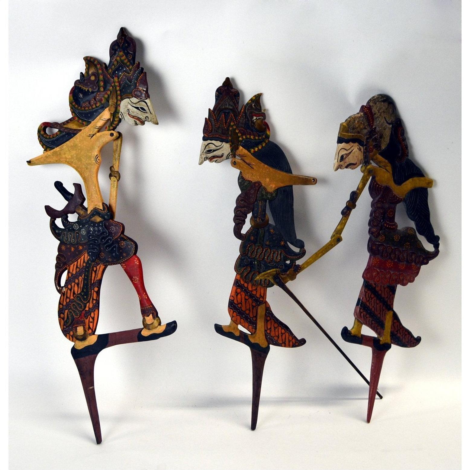 Painted wooden Wayang Kulit Indonesian shadow puppets set of 3 with traditional costumes, close-up on display.