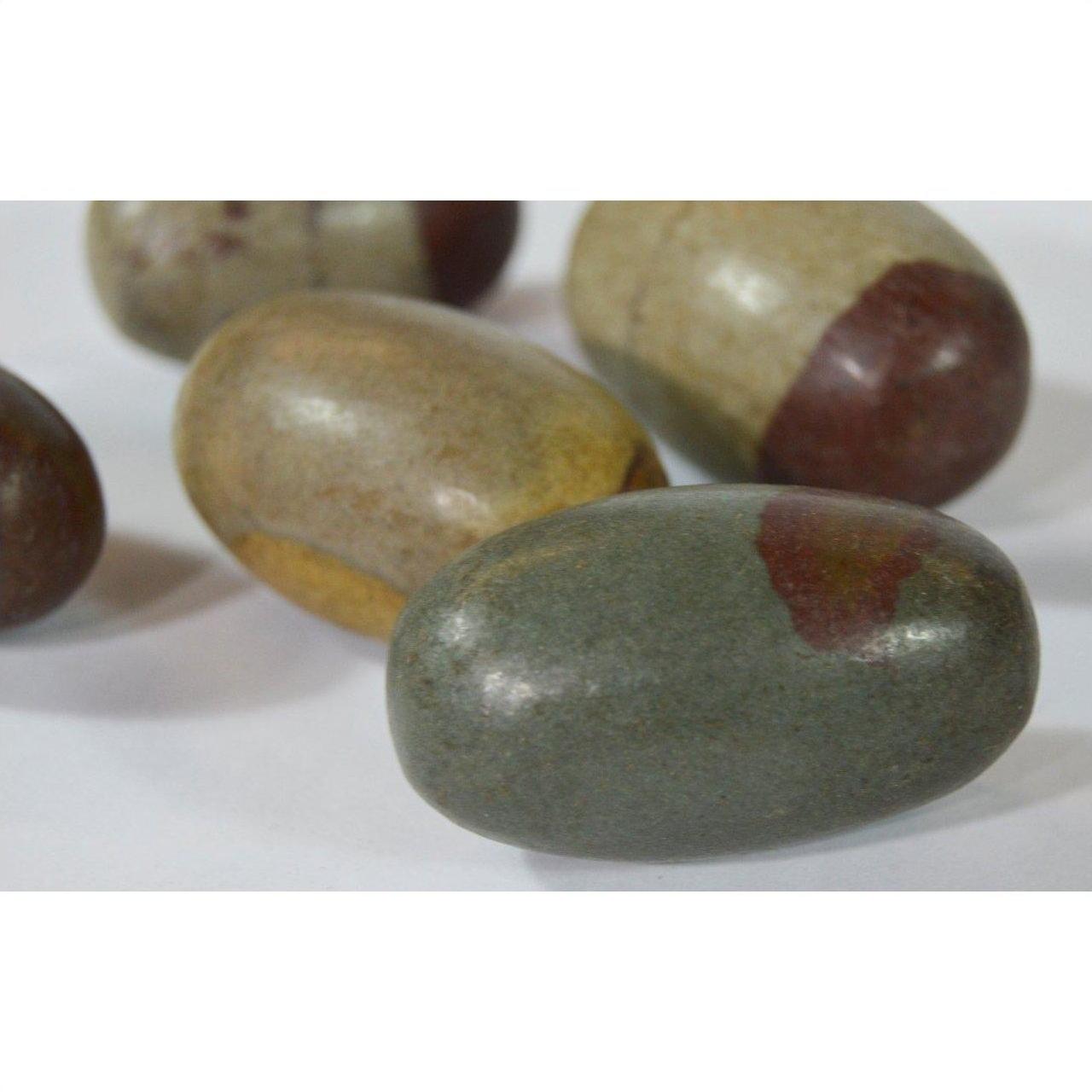 Multicolored oval Shiva Lingam fertility stones, stone material, close-up on white background.