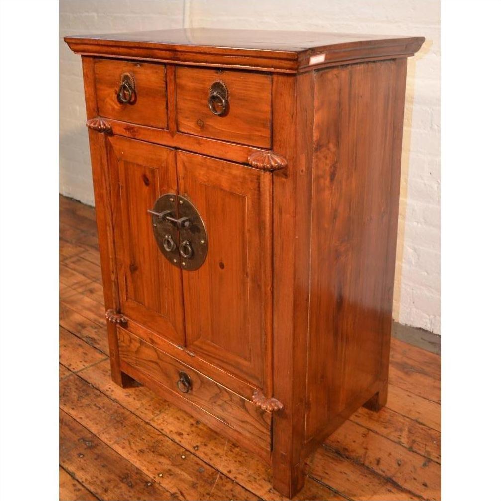 Brown wooden side cabinet with two drawers, double doors, and decorative carvings on a hardwood floor.