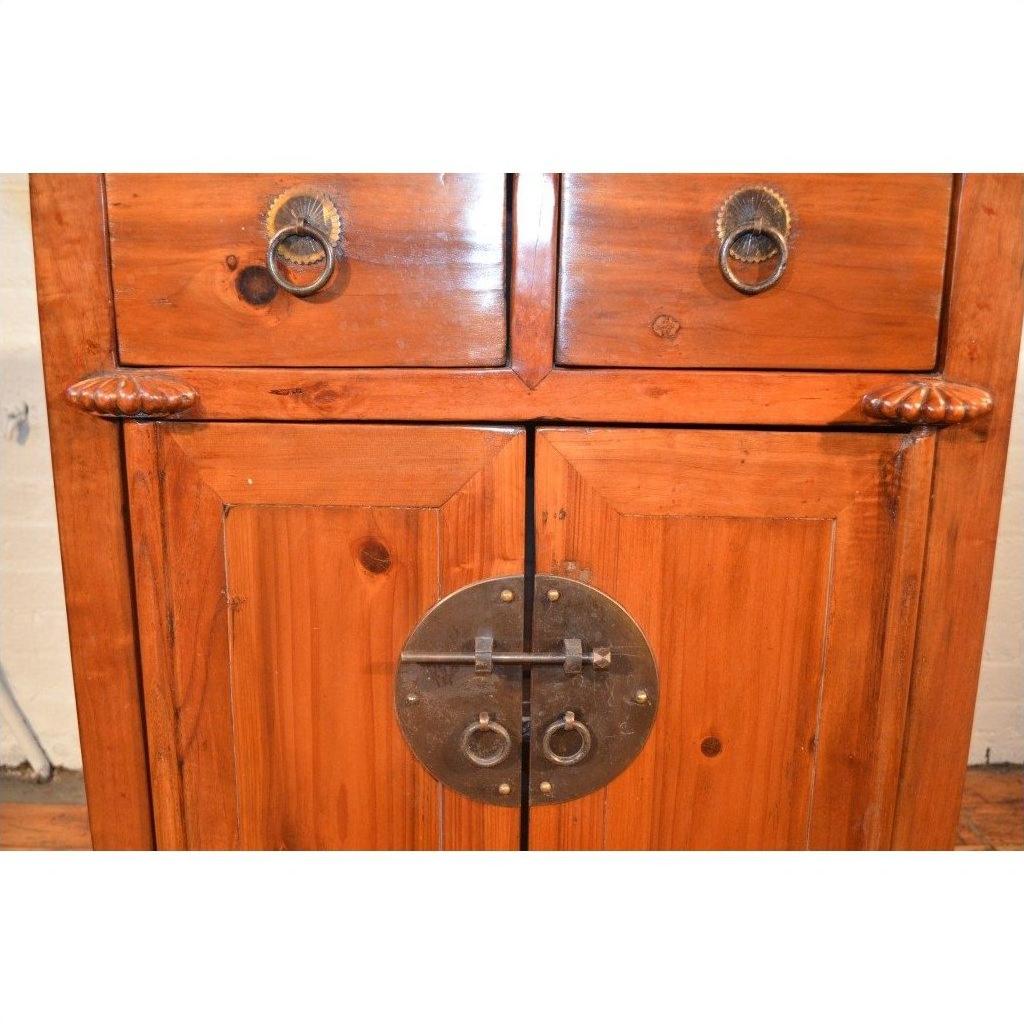 Brown wood side cabinet with two drawers, two doors, and round brass lock with ring handles on front.