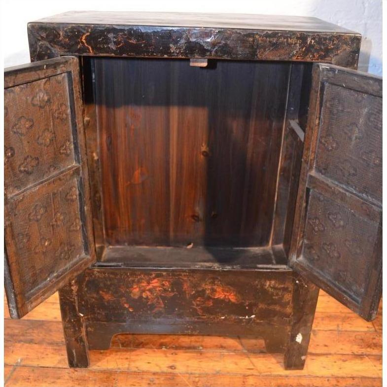 Wooden side cabinet with original decoration, open to show empty interior, placed on a wooden floor.