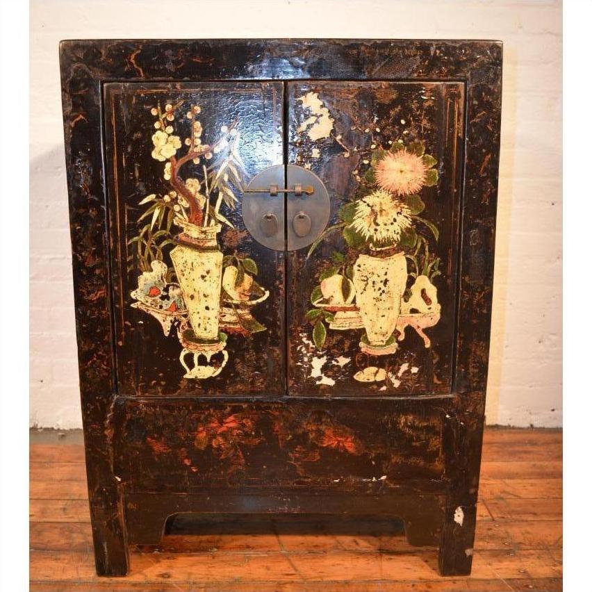 Wood side cabinet with floral vase decorations, round metal handle, placed on a wooden floor, close-up view.