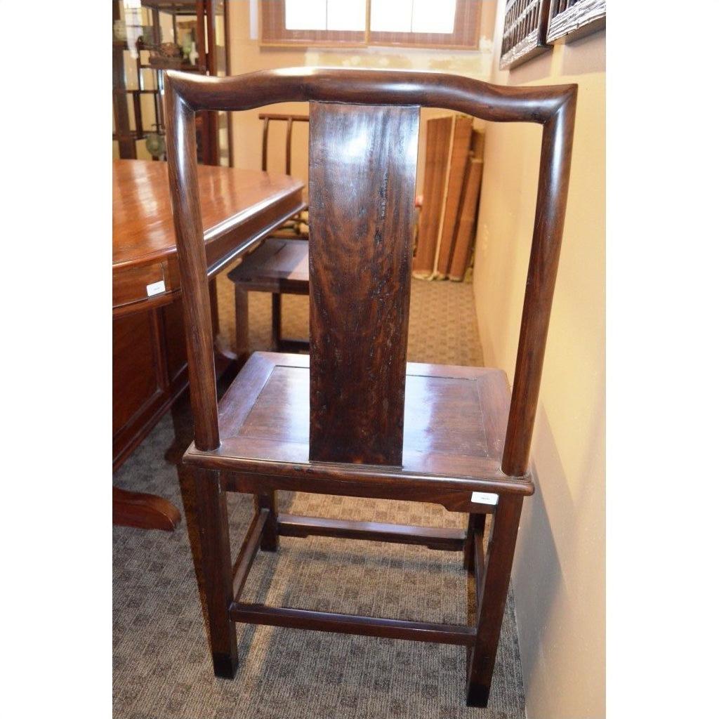 Dark wood side chair with tall back and square seat next to dining table in carpeted room.