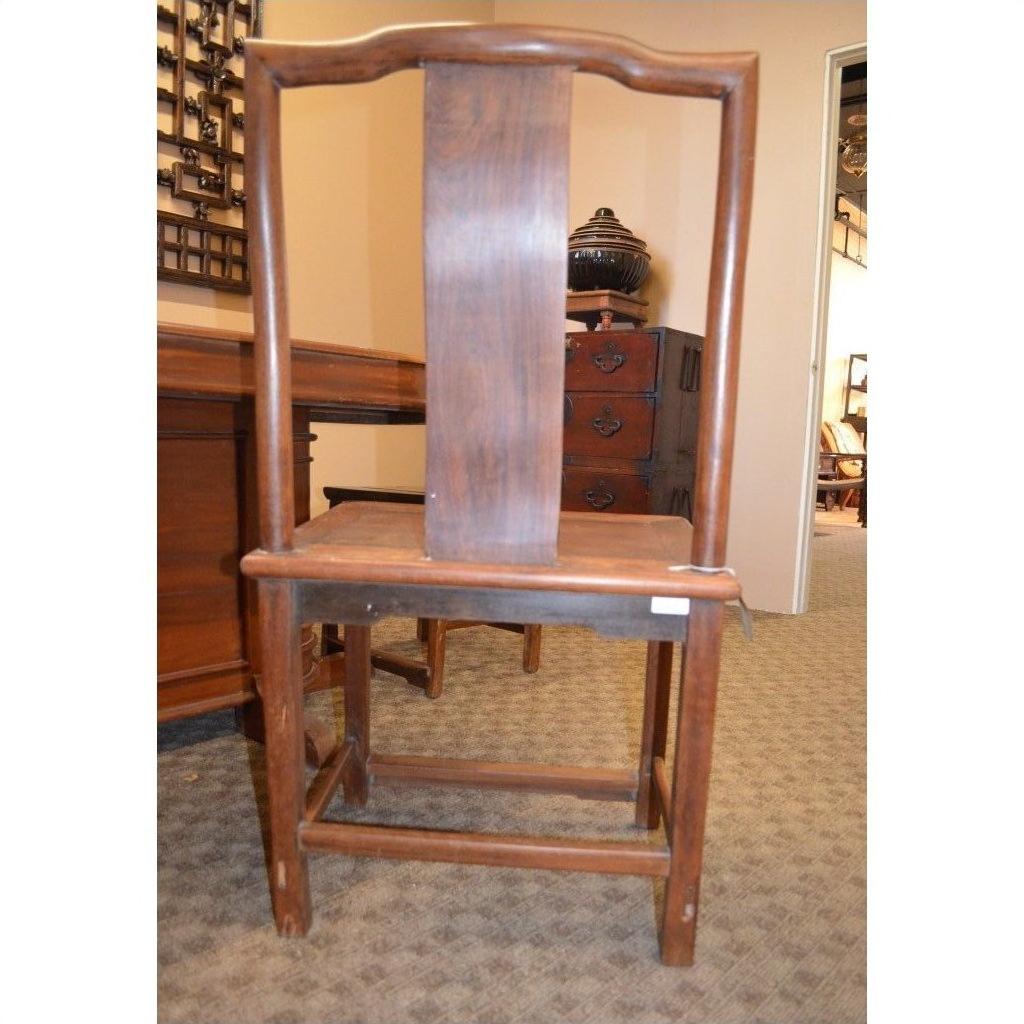 Wooden side chair with a tall, curved backrest and wide central panel in a carpeted room.