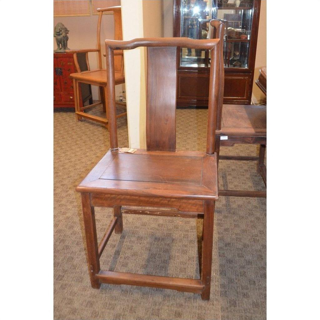 Wooden side chair with tall, straight backrest and square seat on a carpeted indoor floor.