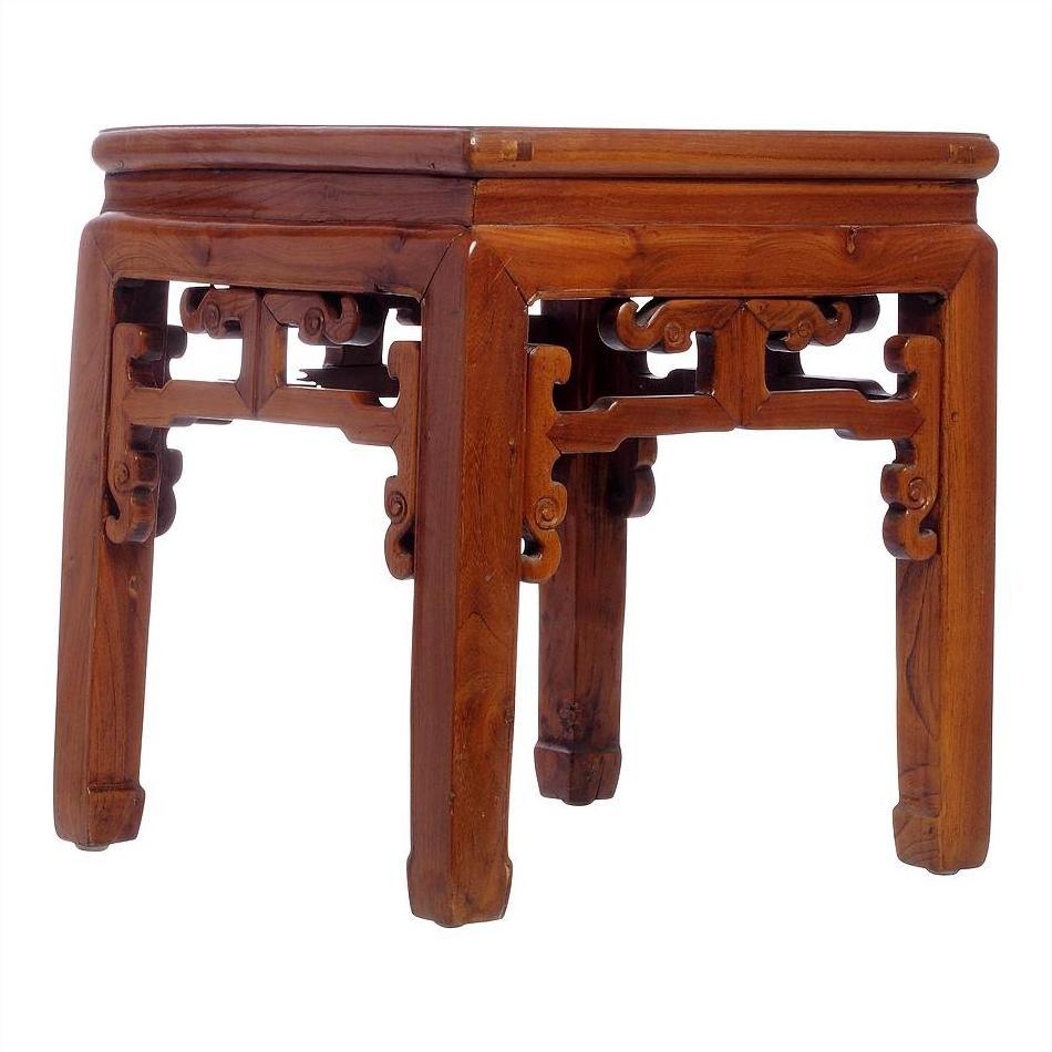 Natural wood side table with decorative carved legs and geometric underside, close-up view.