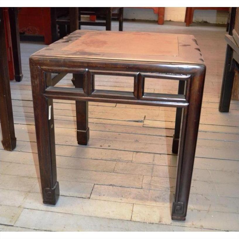 Square dark wood side table with block legs and a worn top, placed on a light wood floor.
