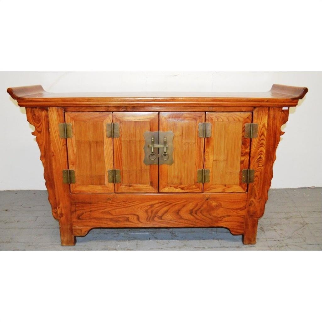 Wooden sideboard with everted flanges, ornate carvings, brass hardware, and double doors against a plain background.
