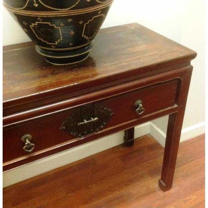 Dark wood console table with horse hoof legs and metal handles, large black bowl on wooden floor.