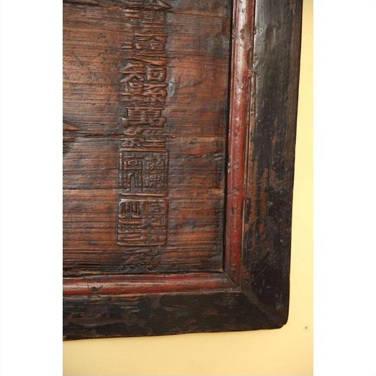 Close-up of yellow wooden signboard corner with vertical Chinese carvings, detail view.