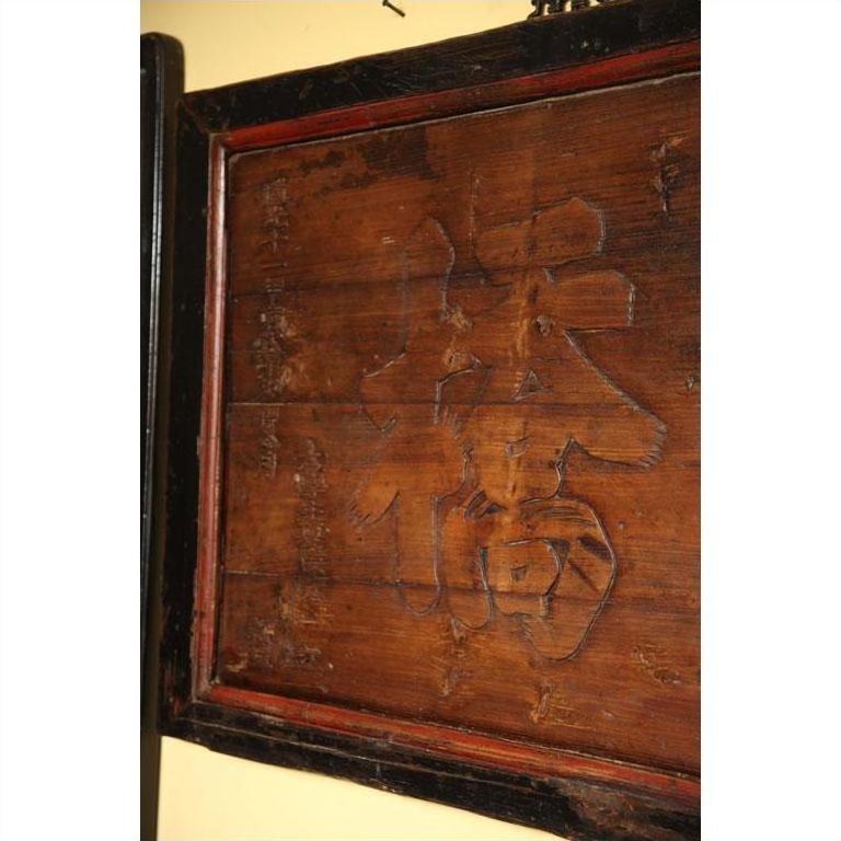 Brown wooden signboard with inscribed text.