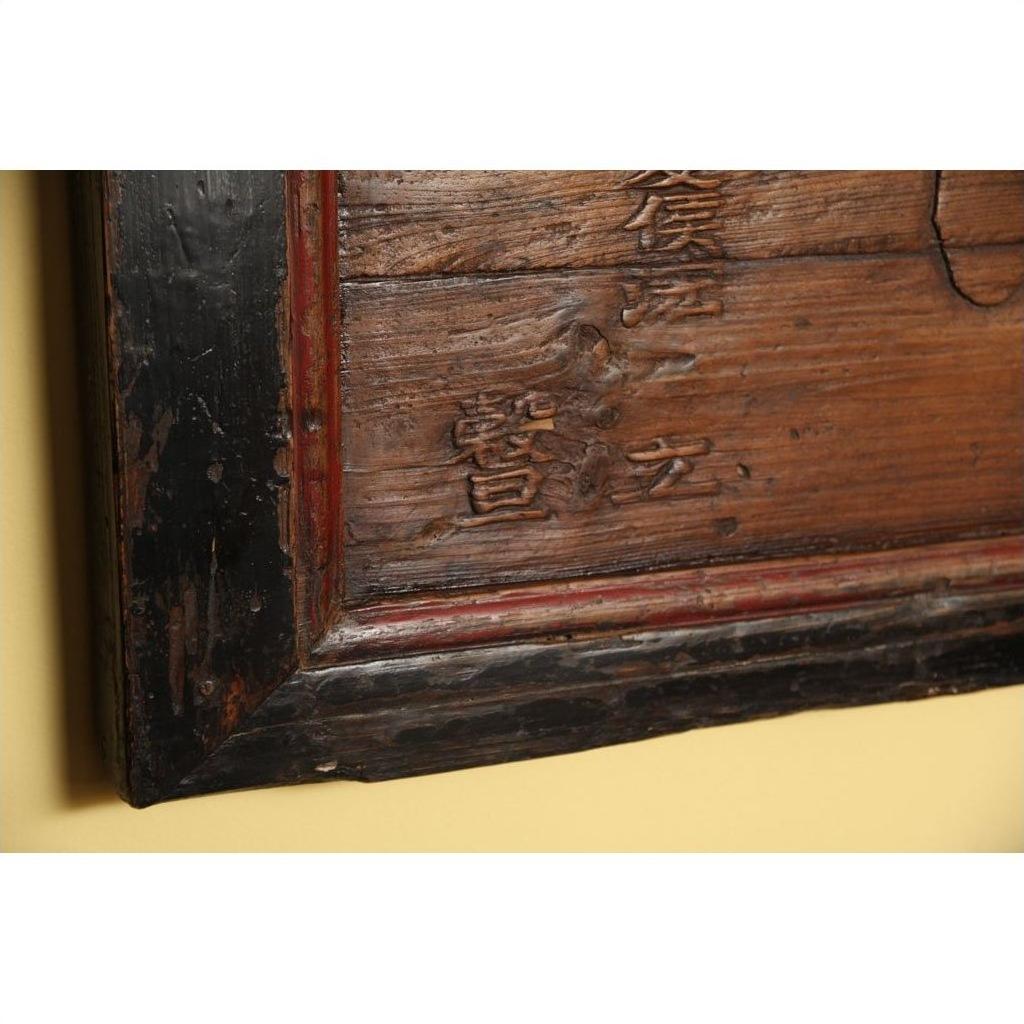Black metal-framed signboard with Chinese characters on a yellow wall.