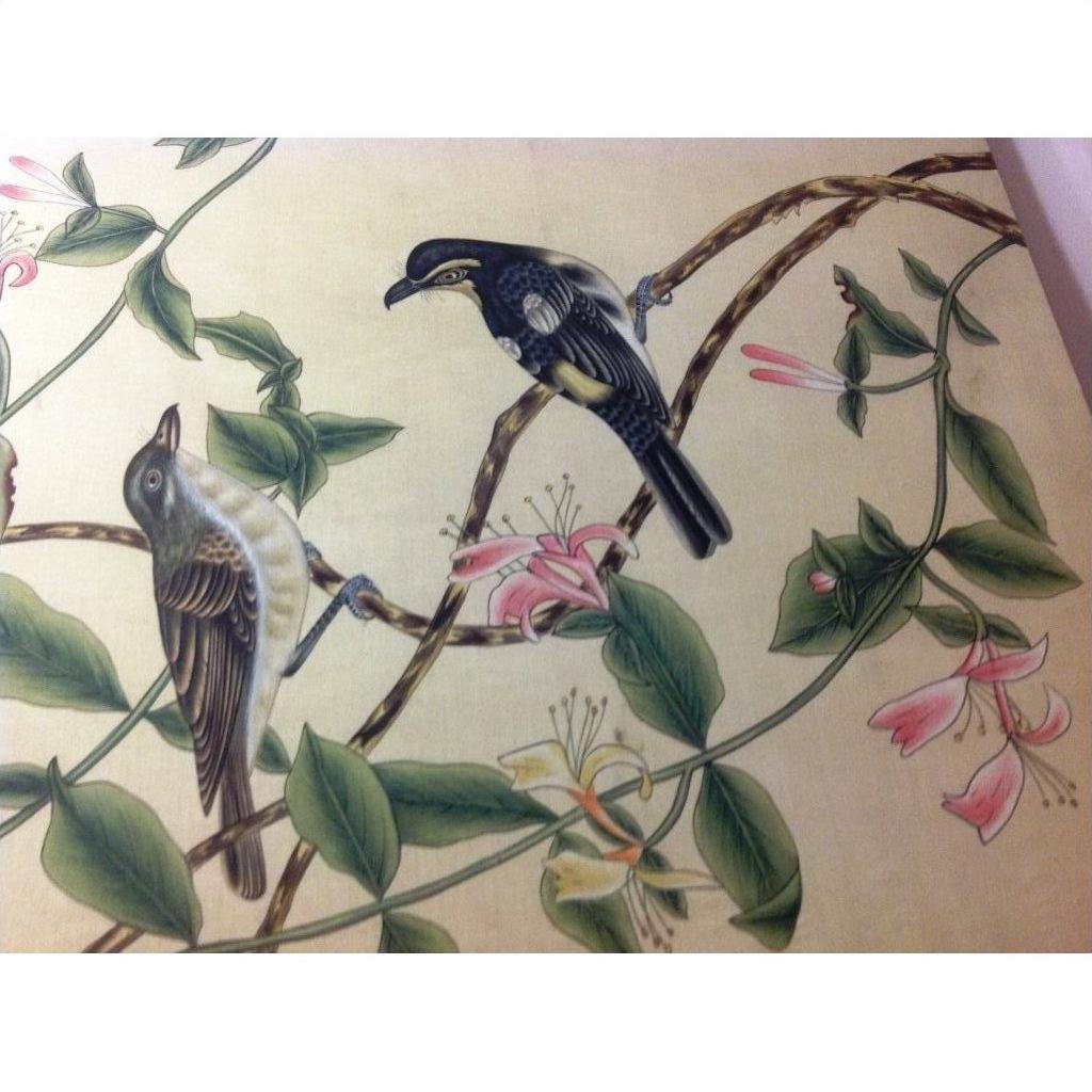 Silk painting with two birds perched on a branch with green leaves and pink blossoms on a light background.
