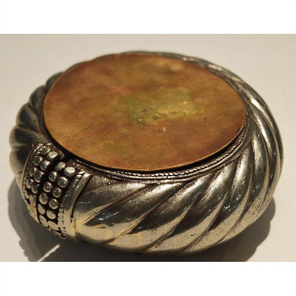 Close-up of silver and brass dancer bracelet wine holder with round, textured, twisted design and flat lid.