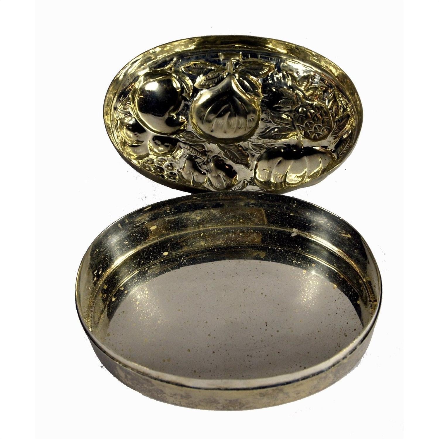 Silver plate jewelry box with ornate fruit designs inside the lid and empty interior, close-up on plain background.