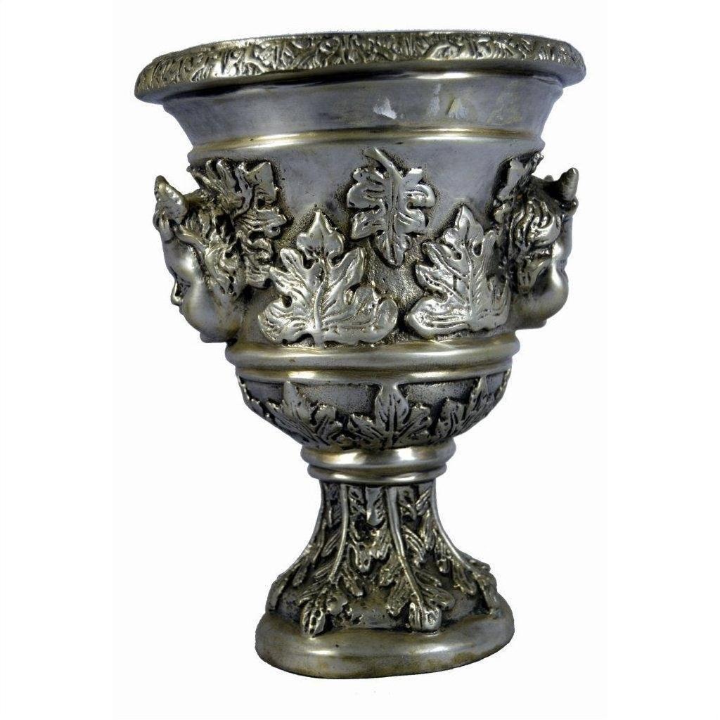 Silver plate urn with embossed leaves, faces, and cherub ornaments on base and body, close-up.
